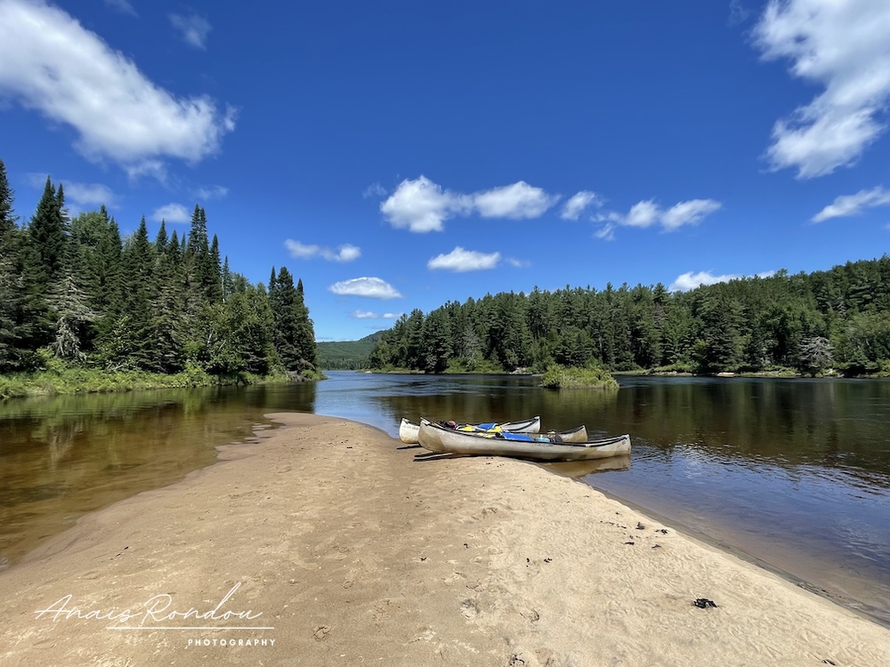 Trois canots posés sur une île au milieu de la rivière Matawin