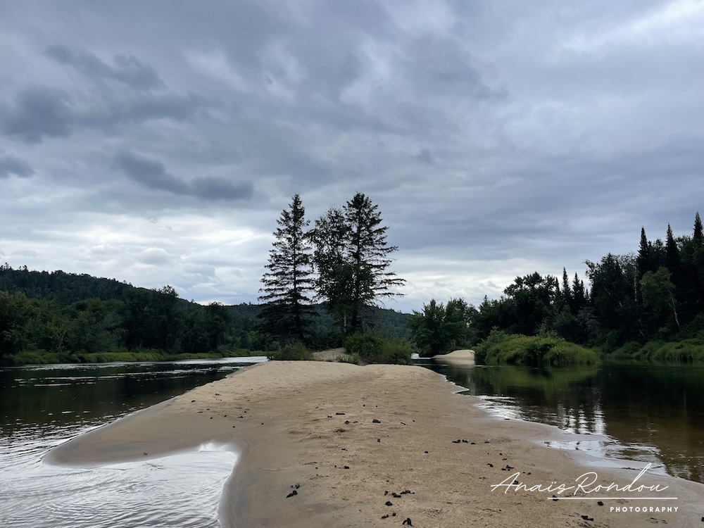 Île au milieu de la rivière sous un ciel nuageaux