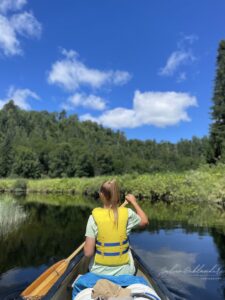 Fille blonde avec gilet de sauvetage qui pagaie dans des méandres