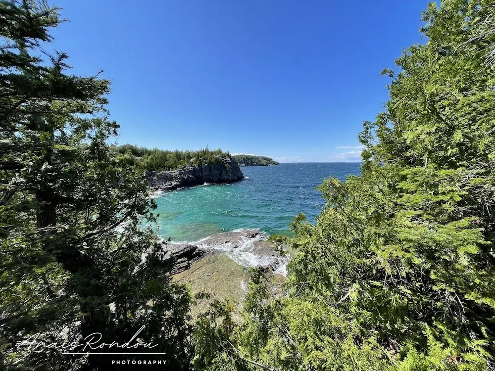L'anse Indian Head et ses eaux turquoises sous un ciel bleu entouré de végétation