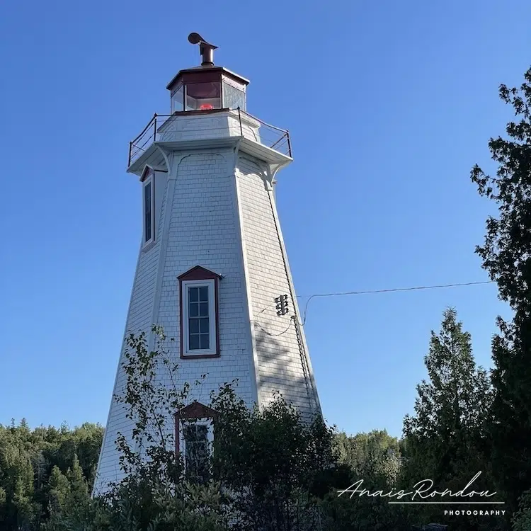 Phare en bois blanc et rouge devant un ciel bleu à Tobermory