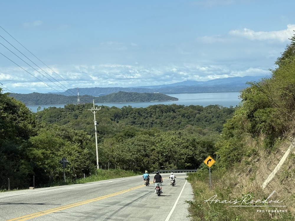 Route du Costa Rica avec vu sur des montagne, de l'eau et des motards