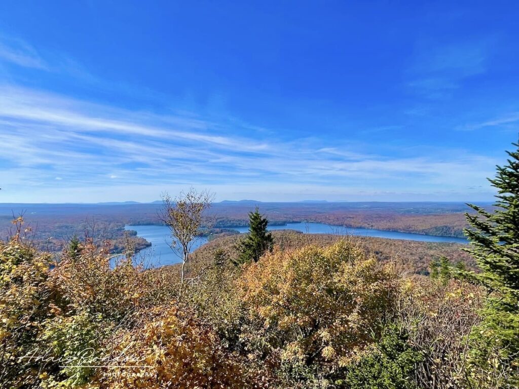 Vue depuis le sommet du Mont Chauve sur un lac et une vallée colorée à l'automne