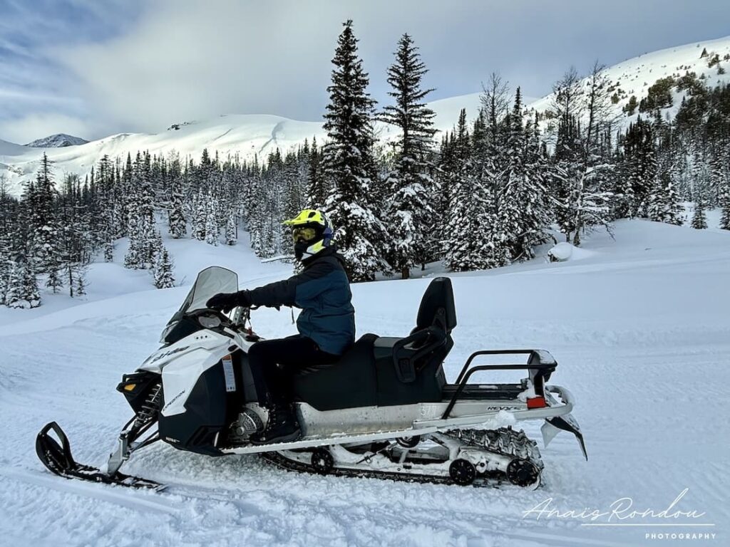 Motoneige Rocheuses canadiennes Personne sur une motoneige dans les montagnes rocheuses canadiennes remplies de neige