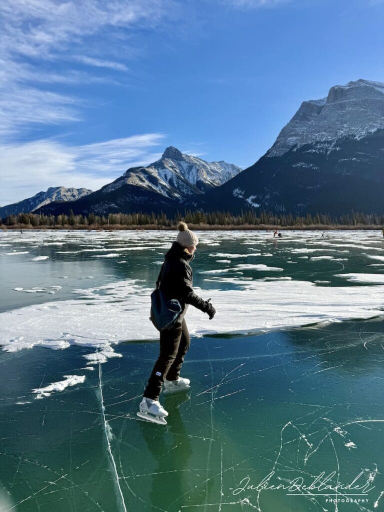 Personne qui patine sur un lac gelé dont la glace est translucide au coeur des montagnes rocheuses canadiennes