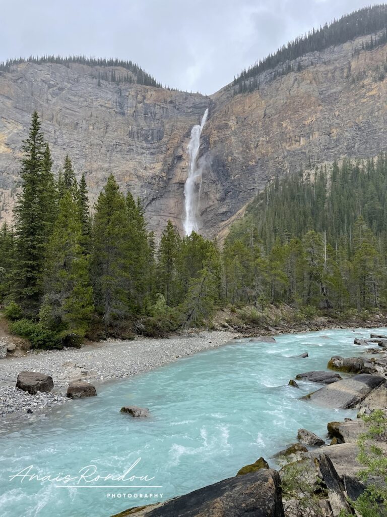 Takakkaw Falls vue de loin avec une rivière turquoise en avant plan